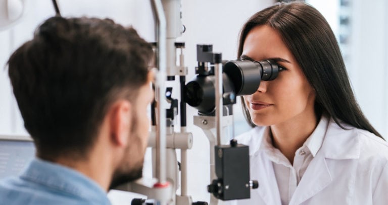 An eye doctor looks into a patient's eyes with a medical device