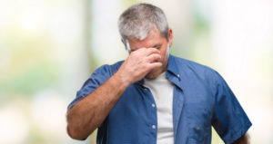 A man squeezes the bridge of his nose with his hand