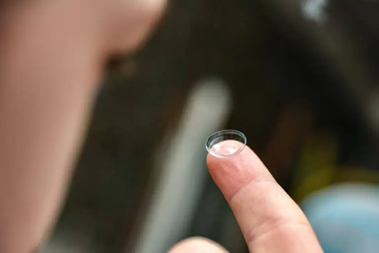 A close-up of a contact lens on a person's finger before use.