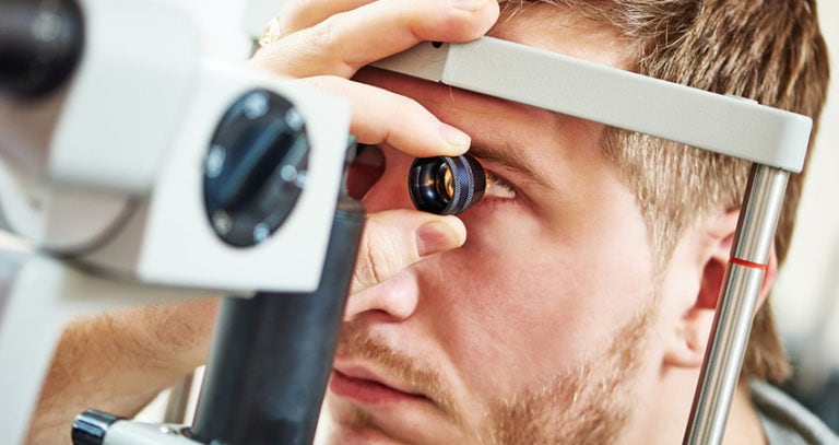 A man is having his eyes examined by a doctor with an eye-exam machine