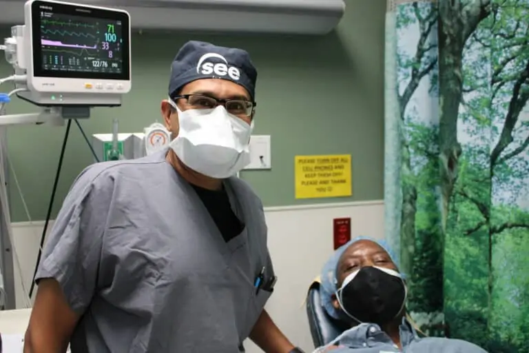 Dr. Ravi Patel stands next to cornea transplant patient Freeman Kelly who is lying in a surgical bed