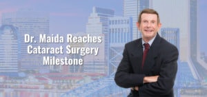 Dr. Maida poses next to text that says "Reaches Cataract Surgery Milestone." Jacksonville skyline in the background.