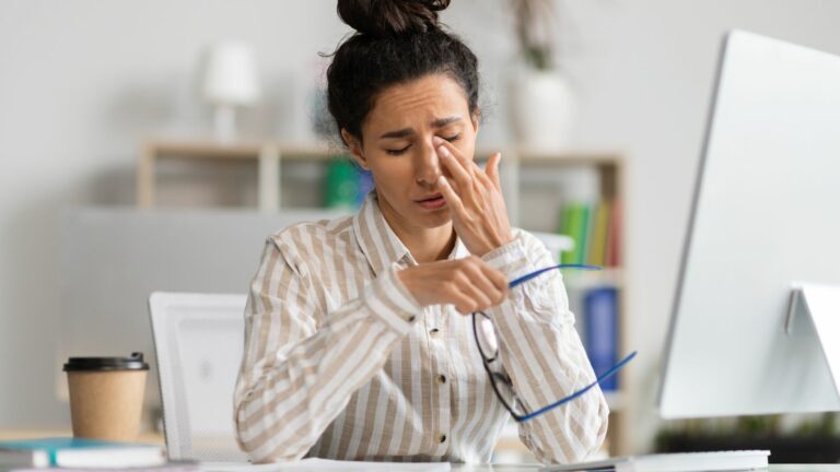 Woman rubbing eyes after taking off her glasses