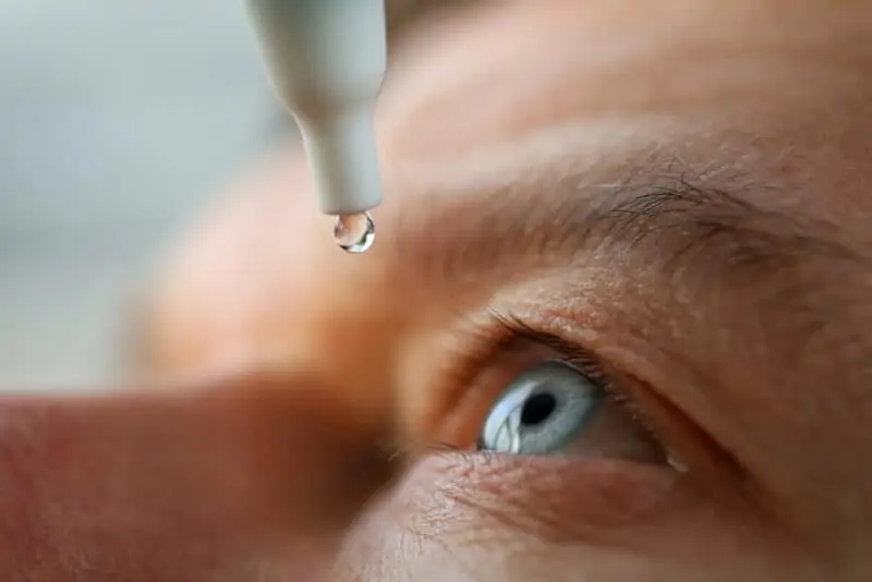 A man drops eye drops into his eye