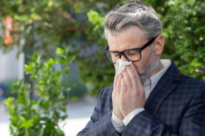 Man blows his nose while sitting on a bench