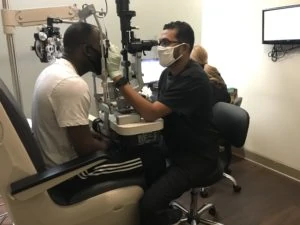 An eye doctor sitting down with patient to examine patients eyes using medical equipment