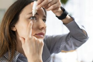 A woman inserts eye drops