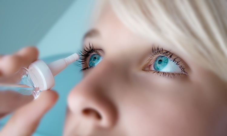 A woman puts eye drops into her eye