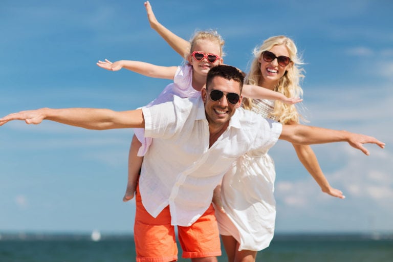 A man, woman and young daughter all wear sunglasses and smile