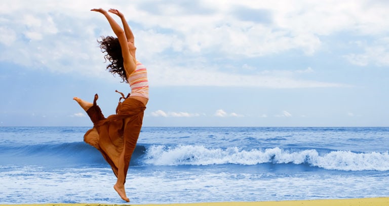 A woman jumps near the shoreline at the beach