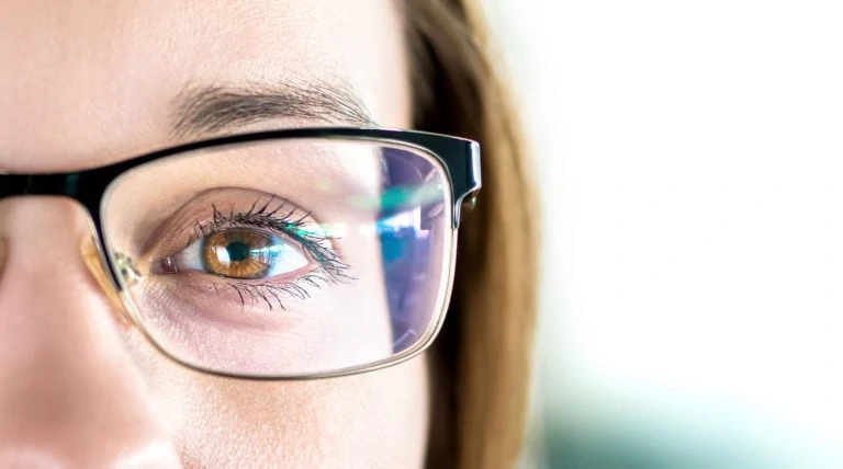 A close-up of a woman's brown eyes. She is wearing glasses