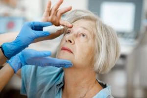 older woman receiving eye drop treatment from nurse