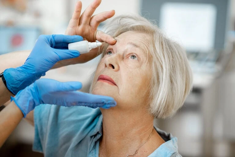 older woman receiving eye drop treatment from nurse